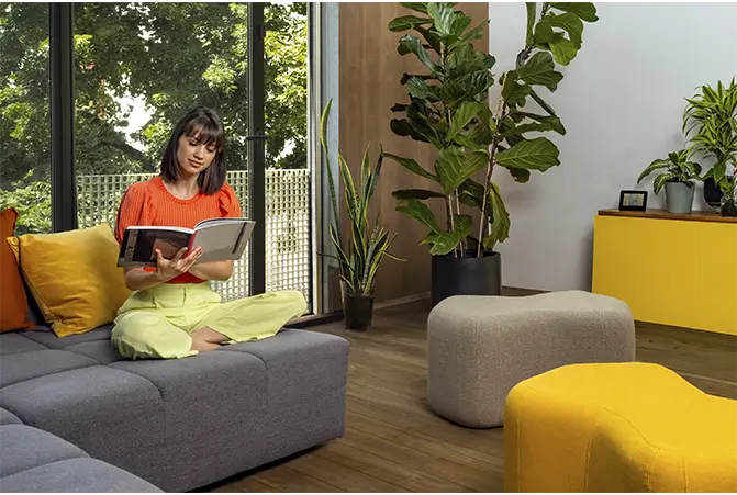 Person sitzt auf dem Sofa im Wohnzimmer und liest in einem Katalog