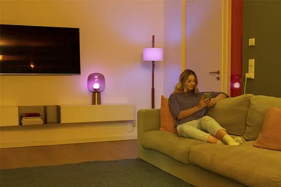 Person sitzt bei gedämmtem Licht auf dem Sofa und bedient das Smartphone