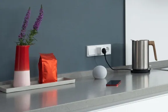 Wasserkocher, LED-Lampe und Smartphone liegen auf Küchenzeile
