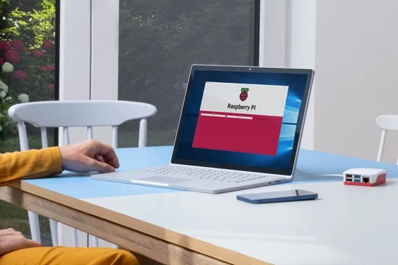 Person sitzt am Tisch vor einem Laptop, auf dem Bildschirm ist Raspberry Pi zu lesen