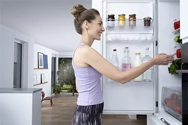 Person schaut in den geöffneten Kühlschrank