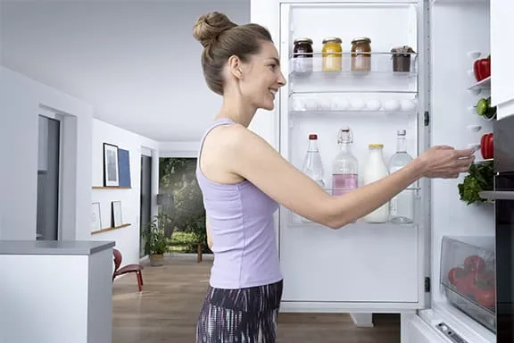 Person schaut in den geöffneten Kühlschrank