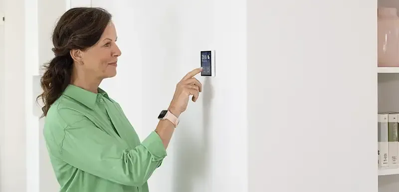 Person bedient das Raumthermostat.
