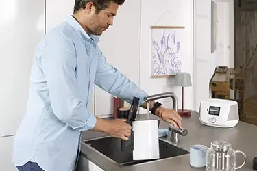 Person füllt den Wasserkocher auf.