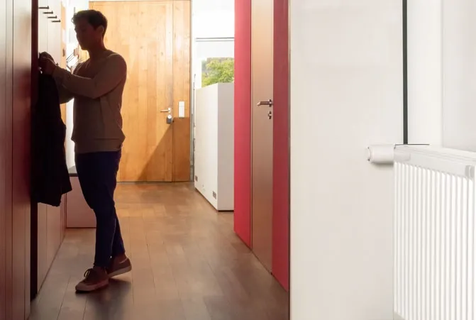 Person steht vor einem wandmontierten Heizkörper.