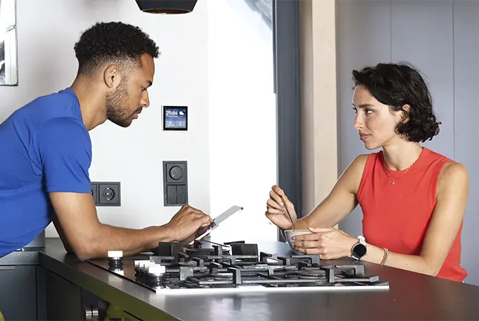 Zwei Personen sind in der Küche und bedienen Smart-Home Gadgets mit dem Tablet.