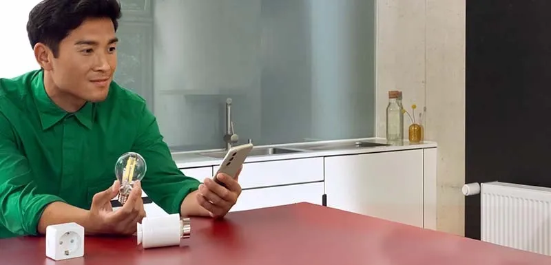Ein Mann richtet mehrere Smart Home Artikel an seinem Smartphone ein.