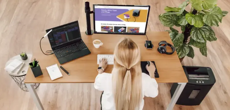 Arbeiten am Computer Blonde Frau sitzt an einem Schreibtisch und arbeitet am Computer.