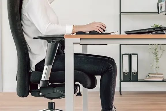 Person sitzt aufrecht am Schreibtisch. Person sitzt aufrecht am Schreibtisch.